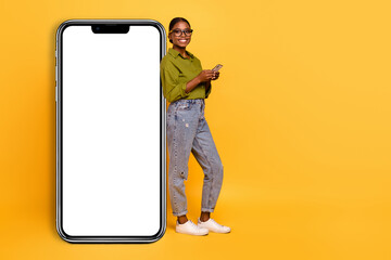 Full length body size view of attractive cheerful girl using gadget copy blank space isolated over bright yellow color background