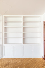 White wardrobes from floor to ceiling along the walls in the room. Many shelves for various interior items, books. From below lockers with doors for clothes, bed linen. The floor is wooden parquet.