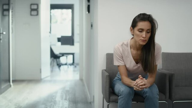 Wide shot of stressed caucasian woman sitting in clinic waiting room and squeezing a stress ball. Shot with RED helium camera in 8K.