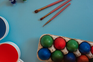 easter theme composition - coloured eggs, paint and brushes on blue background
