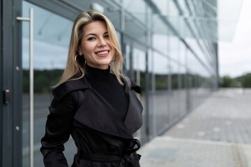 happy young woman stands confidently against the background of a modern building