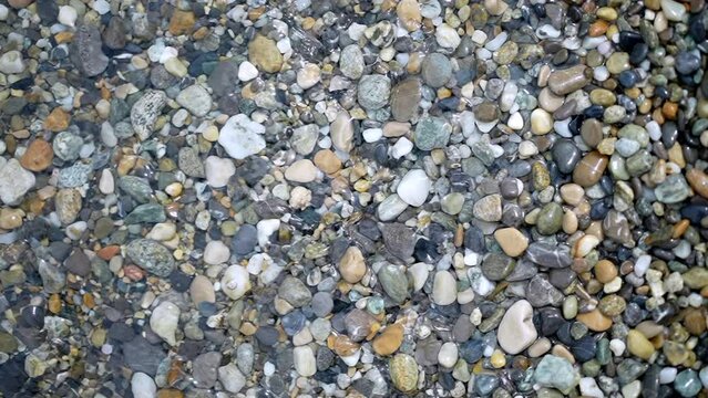 Many diverse rocks at water shore seen from above. Abstract nature background travel relax concept