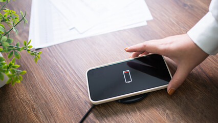 Charging mobile phone battery with wireless charging device in the table. Smartphone charging on a...