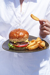 Hands with Burger and potatoes fries, close-up