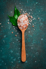 Naklejka na ściany i meble Sea kitchen pink coarse salt in a wooden spoon. On a dark textured background.