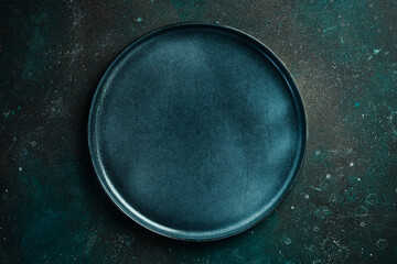 Round blue dinner plate. On a dark green-turquoise background. Free space for text.