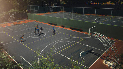 Basketball, outdoor court and athlete men showing energy in ball sports competition or game for fitness and training. Above view, exercise and sport with community people playing streetball together - obrazy, fototapety, plakaty