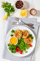 crab cakes with sauce, green peas, tomatoes