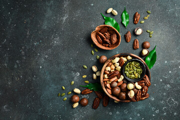 Various Nuts in wooden bowls. Top view. On a dark background.