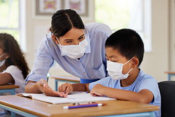 Covid, students and education teacher helping learning children in school classroom to answer math question. Woman with face mask teaching asian boy in lesson with diverse class of kids or classmates