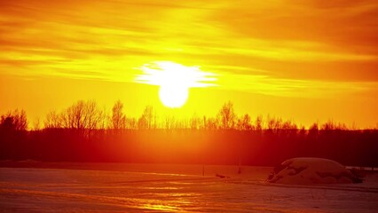 Super bright sunset over rural winter landscape and silhouette of tree line, fusion time lapse - Powered by Adobe