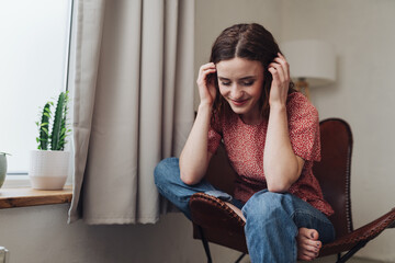 Fototapeta premium Smiling Young Adult Sitting Indoors, Hands on Head