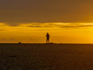 Fototapeta na wymiar Sunrise silhouettes - golden hour romance at the seaside