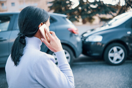 Woman calling insurance roadside assistance after car crash