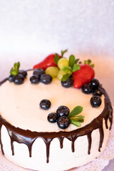 Cake decorated with fruits and chocolate on top.
