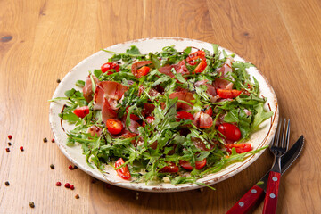 Salad with parma ham on wooden table.