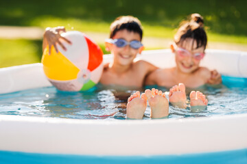 Two children swim in an inflatable pool. Shallow depth of field.