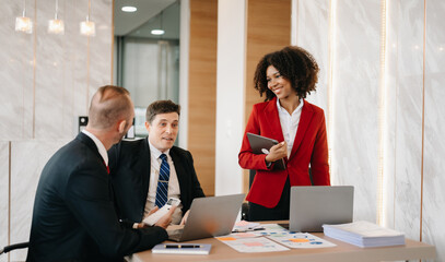 Happy businesspeople while collaborating on a new project in an office. Group of diverse businesspeople using a laptop and tablet in office..