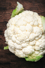 Fresh organic white cauliflower cabbage on old rustic wooden kitchen table background, top view