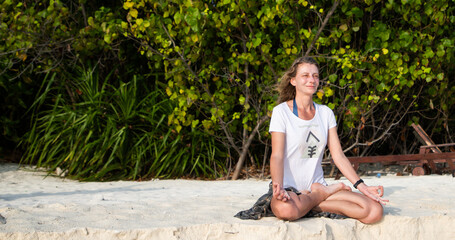 Naklejka premium woman doing yoga on tropical beach