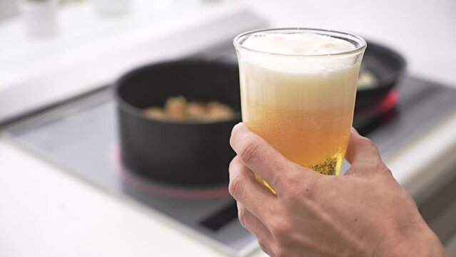 キッチンで料理をしながらビールを注ぐ