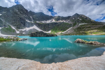 Naklejka na ściany i meble Soft focus. Super wide angle shot. Mountain peaks covered with snow. Lakes with clear blue water.