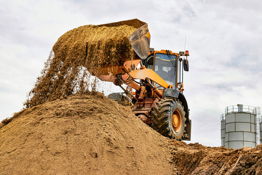 Powerful wheel loader or bulldozer working on a quarry or construction site. Loader with a full bucket of sand. Powerful modern equipment for earthworks.