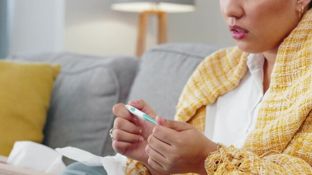 Woman, hands and thermometer checking fever, temperature or flu on living room sofa at home. Hand of sick female patient holding measuring tool for temp reading, healthcare testing or ill symptoms