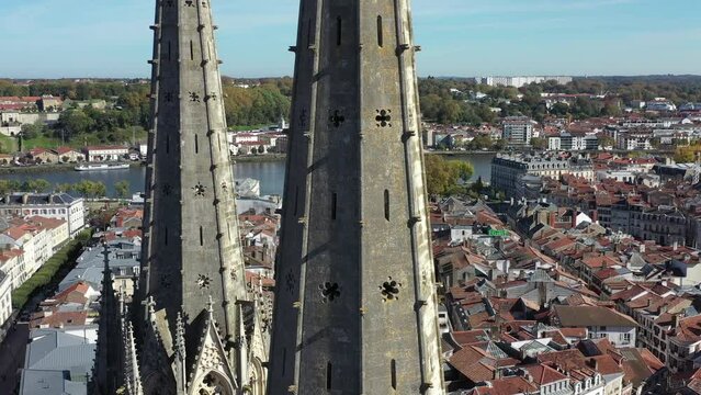 Drone flying around gothic spiers of Bayonne Cathedral with cityscape, France. Aerial orbiting