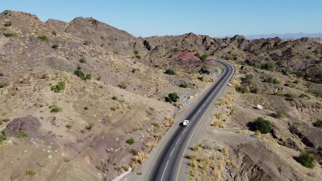 Aerial View Of Vehicle Driving Along Winding RCD Road Through Balochistan. Tracking Shot