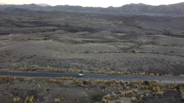 Aerial Parallax Tracking Shot Of Vehicle Driving Along RCD Road Through Balochistan
