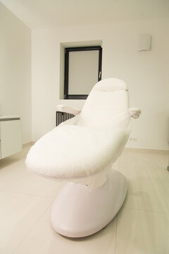 Vertical photo of white cosmetology chair. Clinic interior
