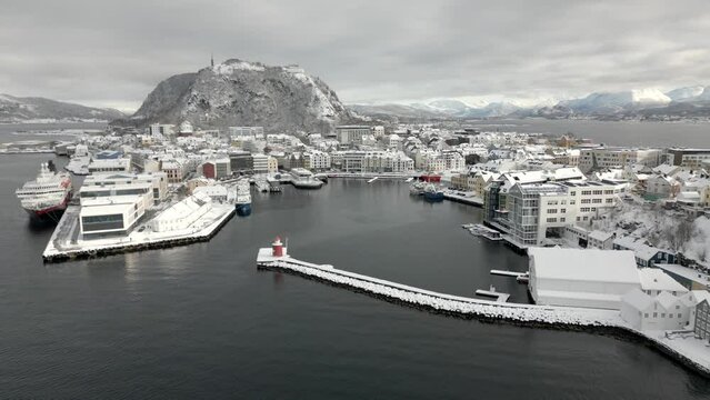 Drone flies backwards from the center of &Aring;lesund towards Asp&oslash;ya and Hessa. The city has recently received a heavy snowfall and is completely covered in snow.