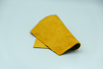 Genuine leather piece isolated on white background. Yellow genuine leather roll. Real leather surface. Hobby and craft material. Manufacture, background textured and wallpaper