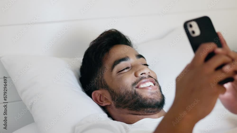 Poster man, phone and smile lying in bed for social media, chatting or texting while relaxing at home. happ