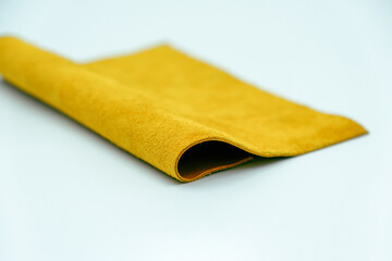 Genuine leather piece isolated on white background. Yellow genuine leather roll. Real leather surface. Hobby and craft material. Manufacture, background textured and wallpaper