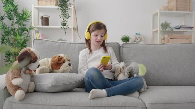Kid having video call on phone sitting on couch at home.