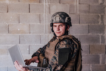 American soldier in military uniform using laptop computer for drone controlling and to stay in...