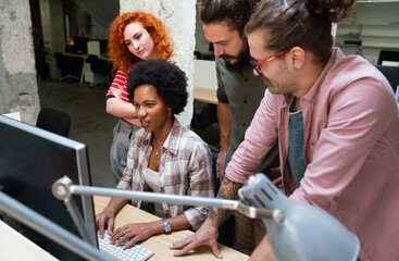 Diverse group of professionals meeting in office. IT programmers use computer, talk strategy