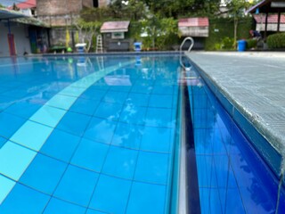Swimming pool with metal stairs handle and deck in the aqua park on sunny day.
