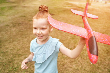 Little girl with airplane toy. Adventure fly concept. Stay home game. Family garden activity. Red...