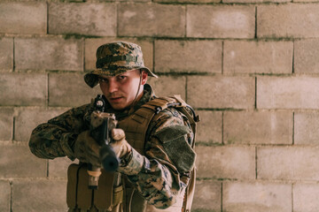 A soldier in uniform stands in front of a stone wall in full war gear preparing for battle