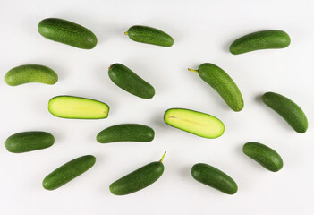 Cut and whole seedless mini avocados isolated on white. A pattern made of a group of mini avocado or cocktail avocado on white background. Green vegan functional food for healthy lifestyle, superfood
