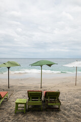 Tropical beach with colorful umbrellas and empty lounge chairs on a cloudy day, peaceful seaside vacation destination.