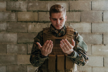 A Muslim soldier of the special forces prays to God by raising his hands and starts a prayer