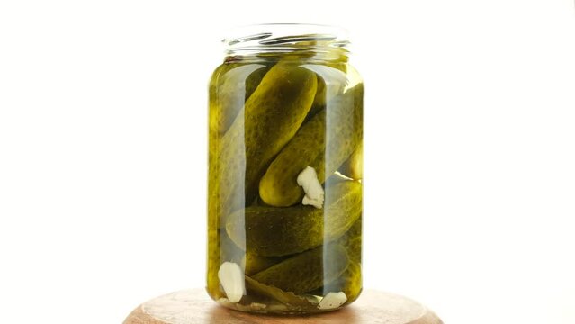 Pickled cucumbers in glass jar, rotation. Condiment on a hamburger or other sandwich