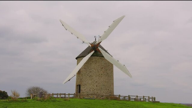 An old windmill in the countryside of Normandy, France. A windmill is a mill that converts the energy of wind into rotational energy by means of vanes called sails or blades