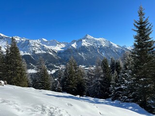 Fototapeta na wymiar Beautiful sunlit and snow-capped alpine peaks above the Swiss tourist sports-recreational winter resorts of Valbella and Lenzerheide in the Swiss Alps - Canton of Grisons, Switzerland (Schweiz)