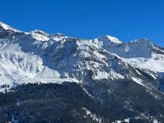 Beautiful sunlit and snow-capped alpine peaks above the Swiss tourist sports-recreational winter resorts of Valbella and Lenzerheide in the Swiss Alps - Canton of Grisons, Switzerland (Schweiz)