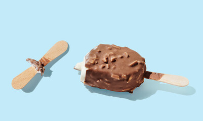 Eaten chocolate ice cream on a stick on blue pastel background